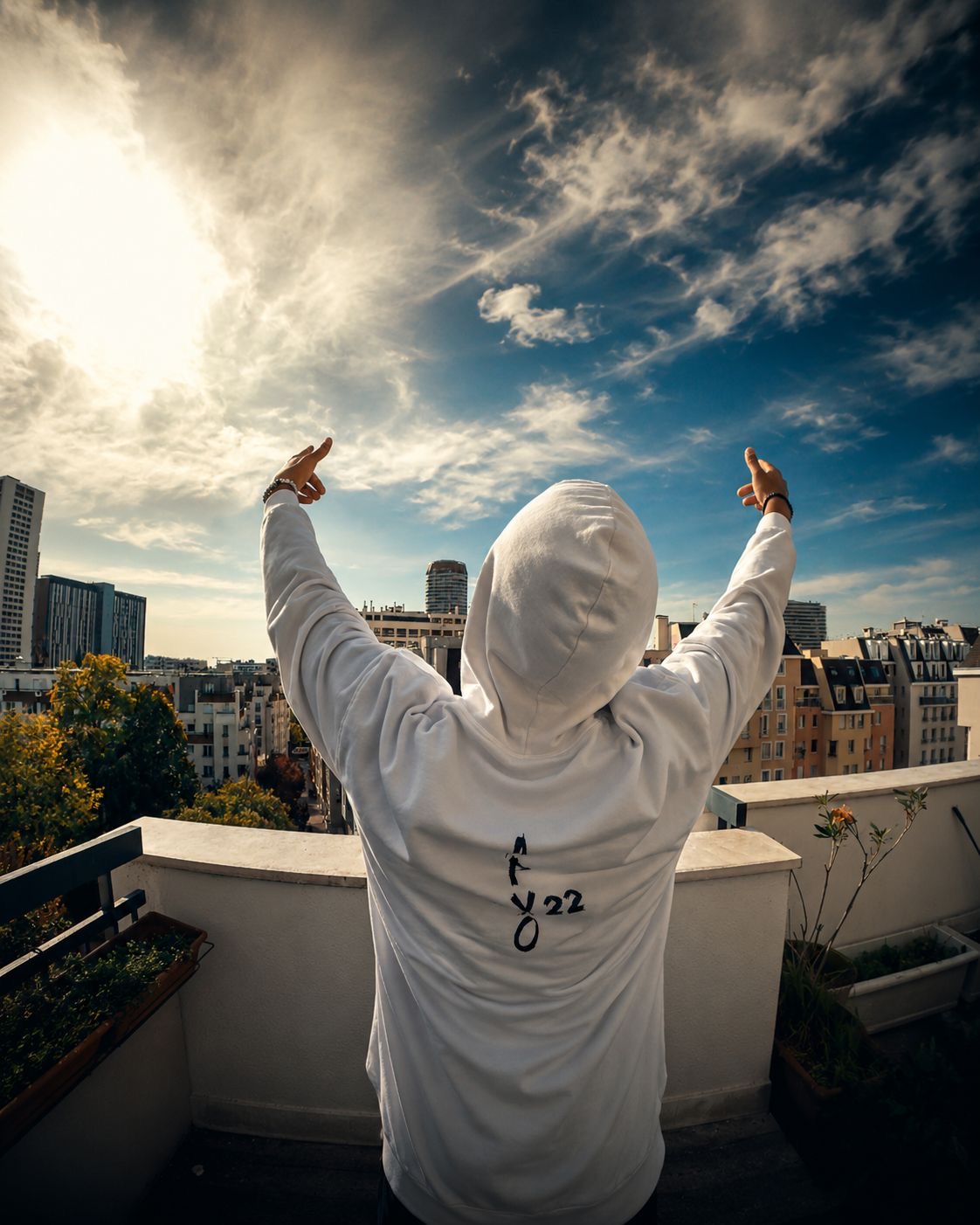 APXO on a Paris rooftop with both arms raised towards a bright sky