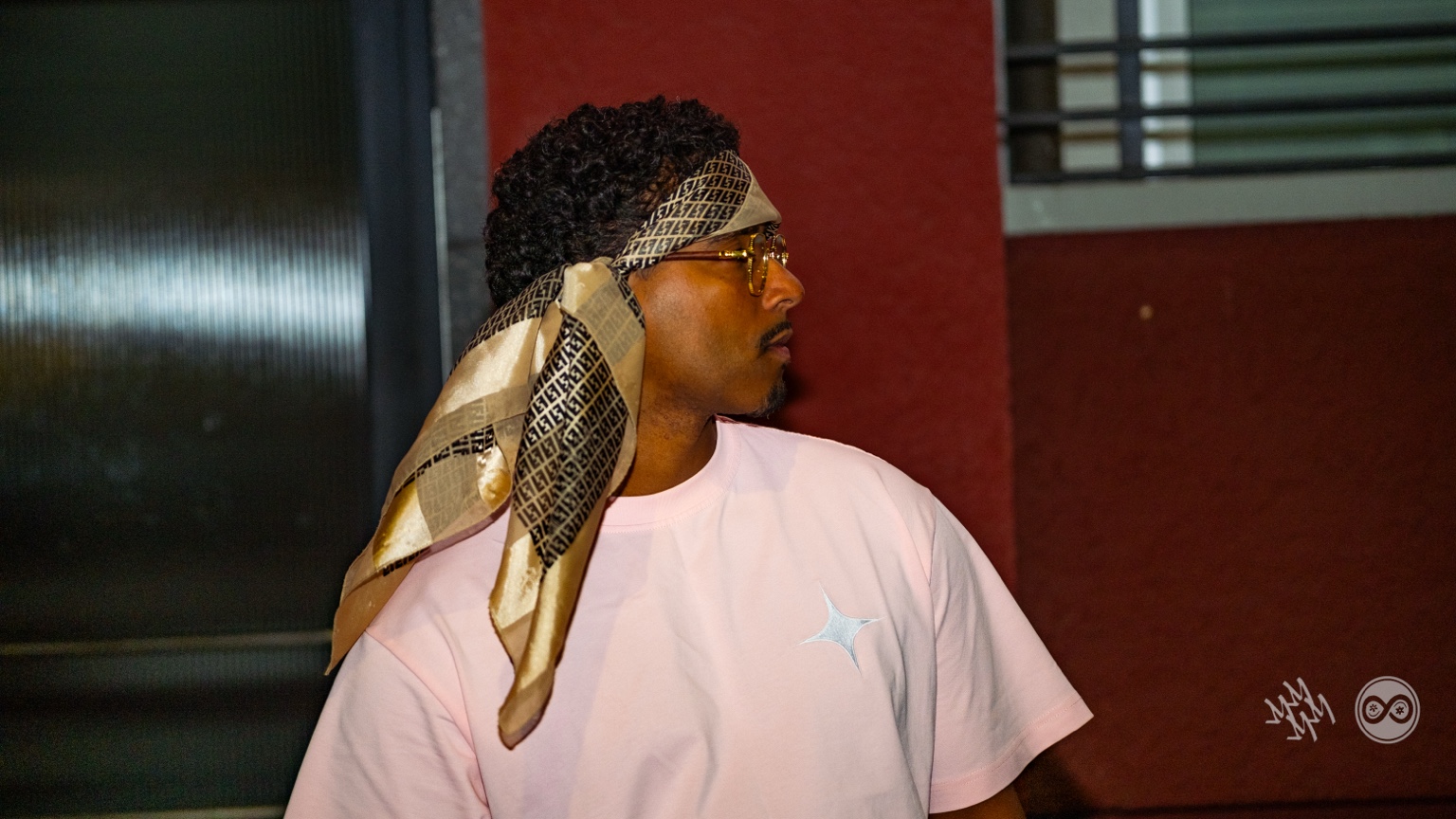 Side profile of APXO wearing a patterned bandana and a pink t-shirt