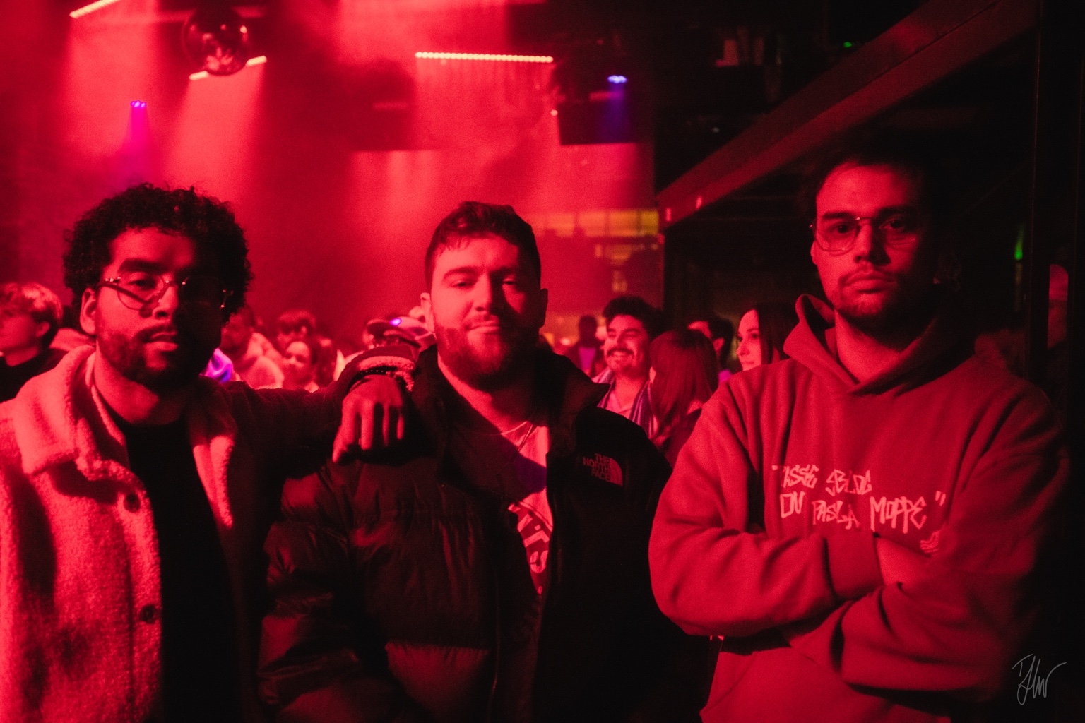 APXO with two others in a dark venue bathed in deep red stage light
