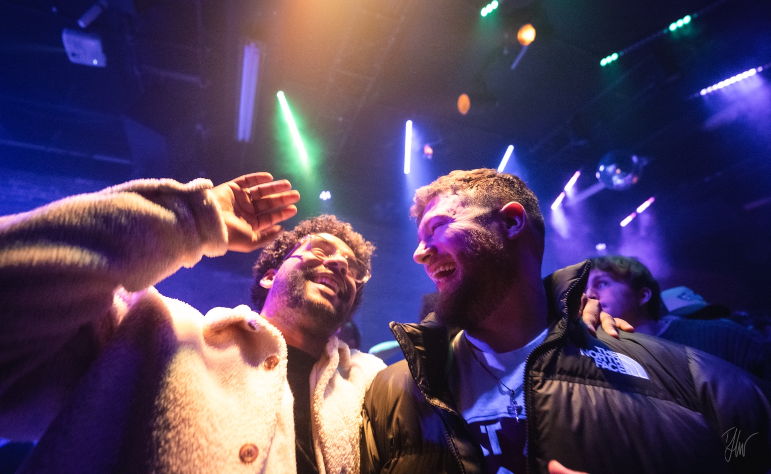 APXO laughing in a club under neon lighting with Avian and 808vybz