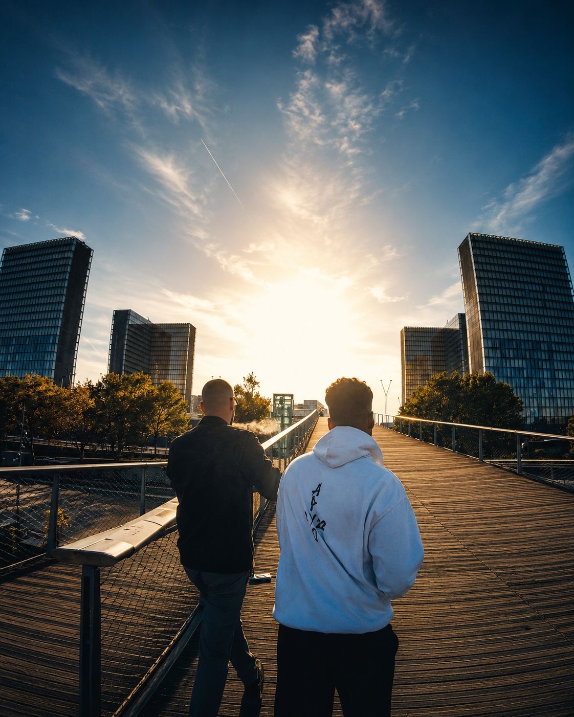 Two figures walking across a wooden bridge in Paris at sunset