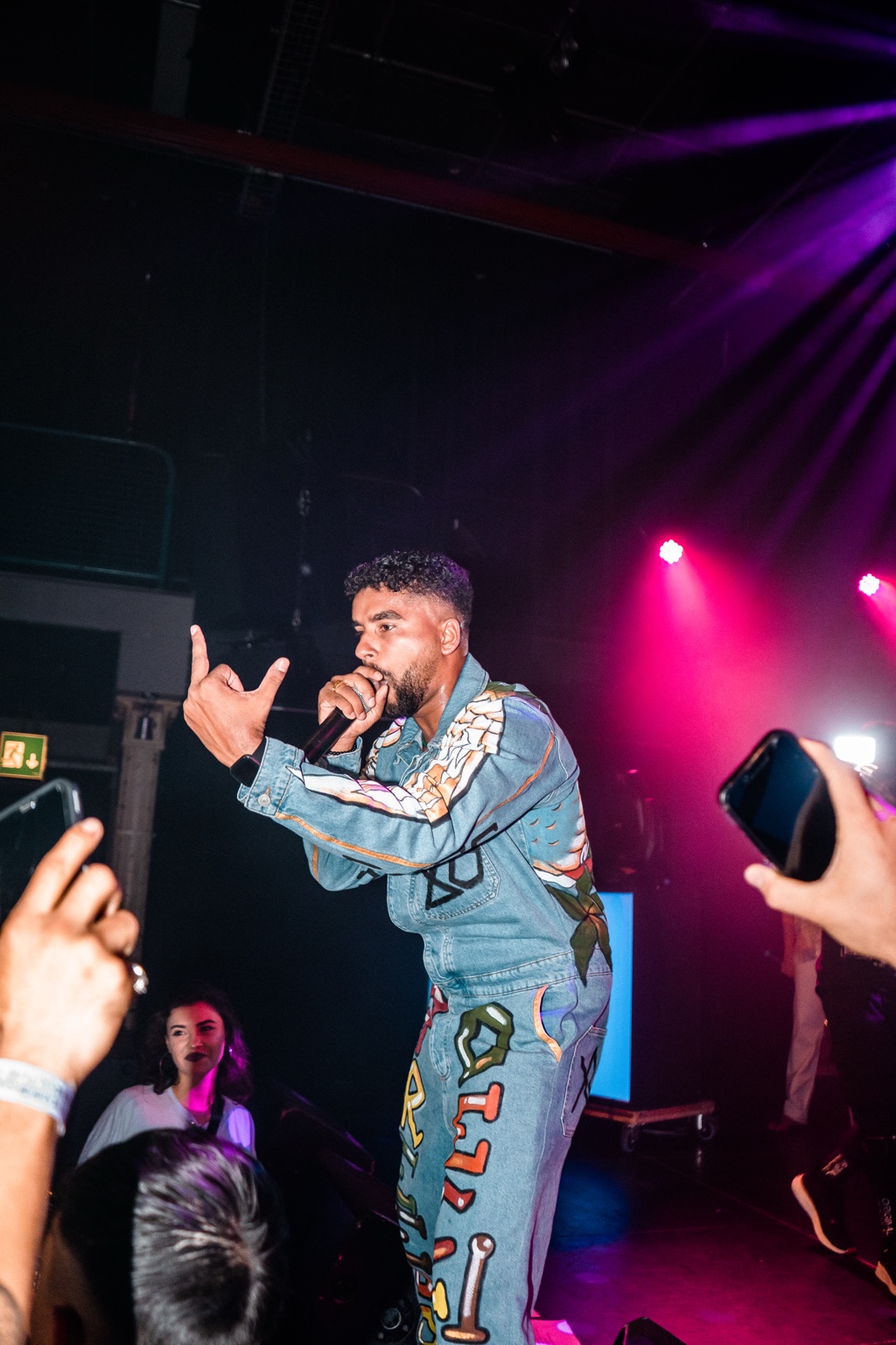 APXO performing on stage in a graphic denim jacket under purple stage lights