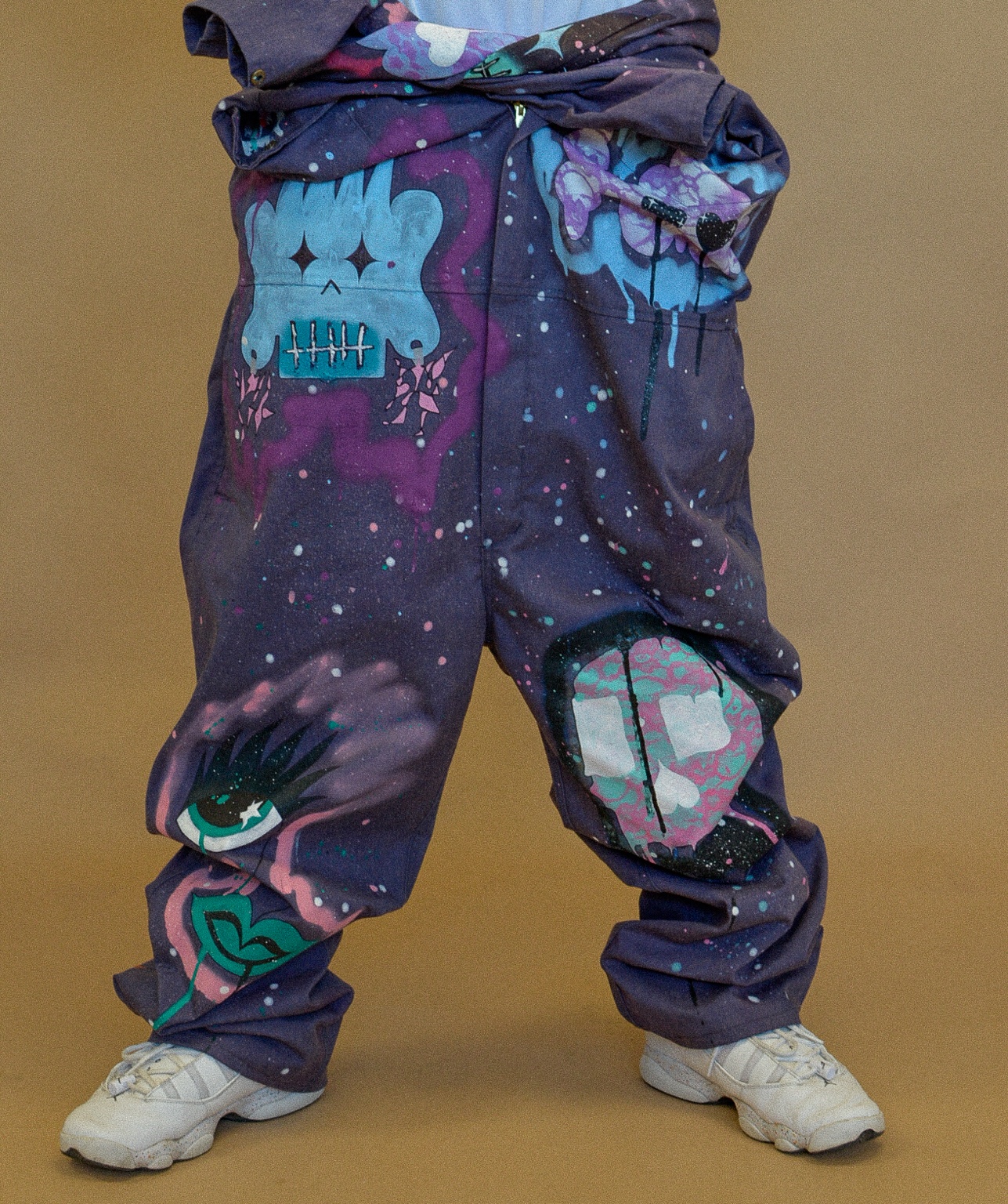 Detail of hand-painted XCYR trousers covered in illustrated characters and paint splatter