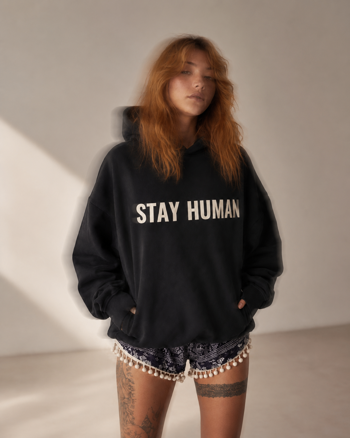 Studio portrait of a woman wearing the oversized Stay Human Heavyweight Hoodie in Black Beauty, cream STAY HUMAN print across the chest.