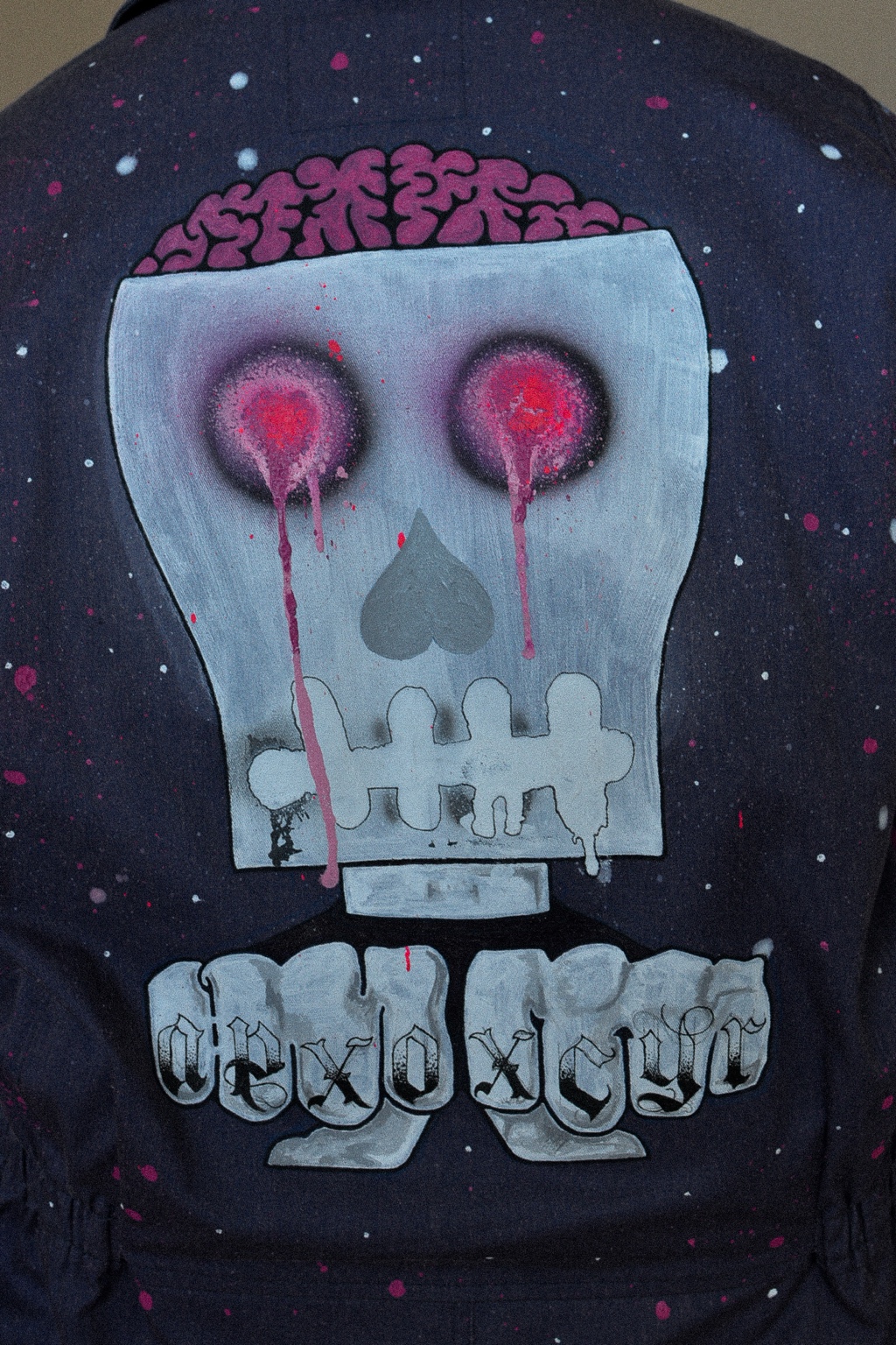 Back of the hand-painted APXO garment showing a large stylised skull graphic